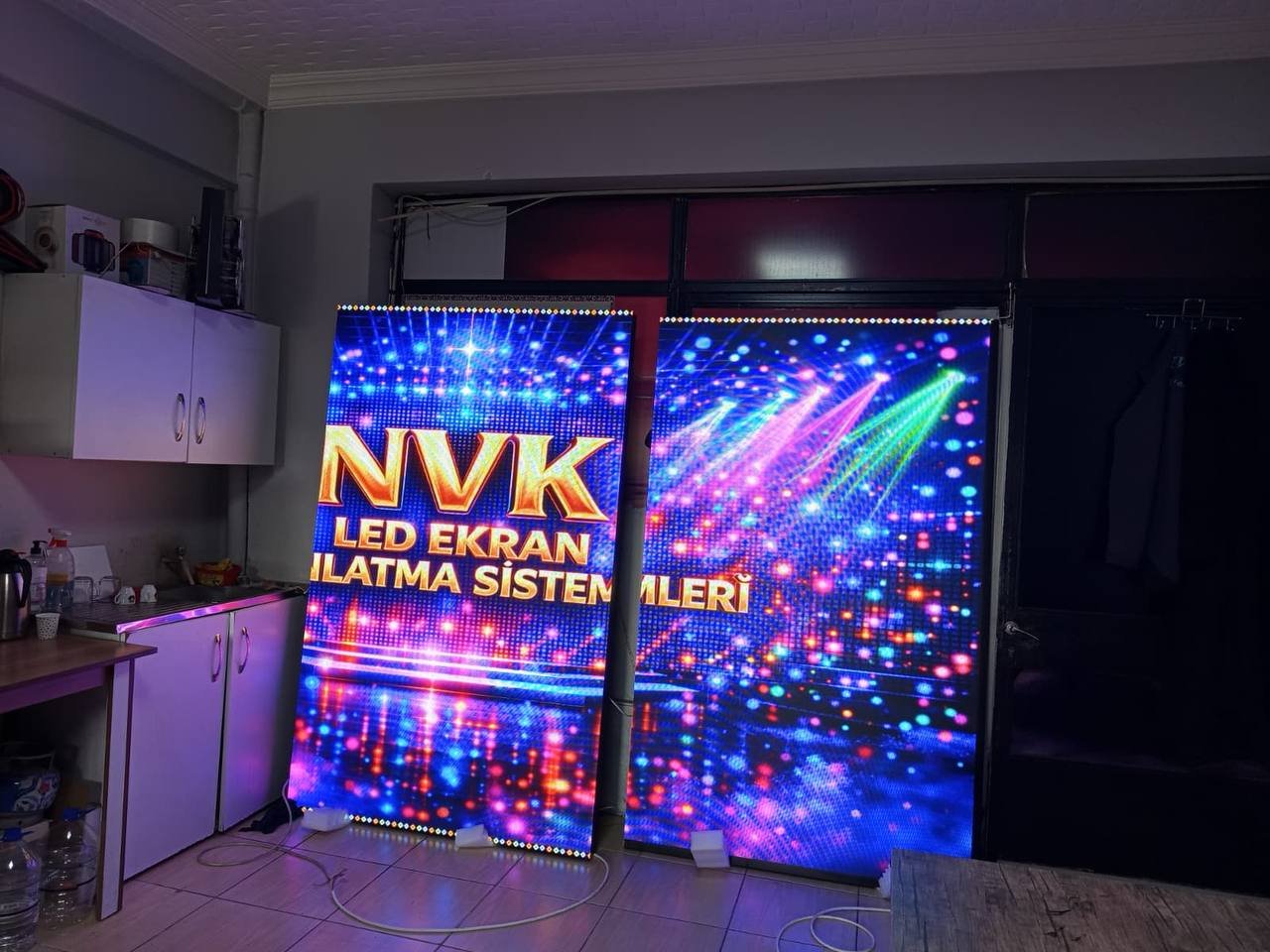 Atölyede NVK içeriği gösteren iki dikey LED ekran
